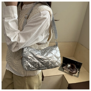 Close-up of silver quilted puffer shoulder bag featuring metallic finish and gold hardware