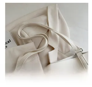 Detail showing high-quality stitching and silver metal buckle on cream faux leather tote bag
