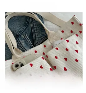 Detail of white corduroy tote bag with red heart pattern and two practical side pockets