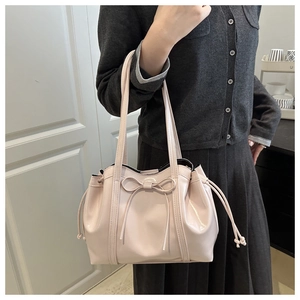 Detail of light pink patent leather tote bag featuring stylish bow and side drawstring