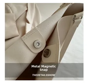 Detail of the high-quality magnetic metal clasp on a cream-colored vintage tote bag
