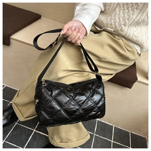 Detail of black quilted shoulder bag featuring rhombic stitching and soft nylon texture
