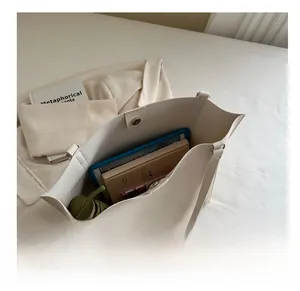 Top-down view of spacious creamy tote bag interior showing books and magnetic clasp