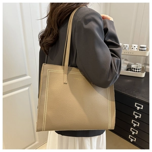 Detail of taupe pebbled leather tote bag with white contrast stitching and slim straps