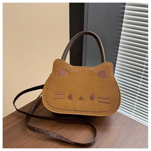Close-up of cute brown cat-shaped bag with embroidery on smooth leather surface