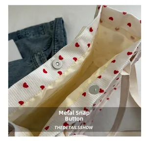 Close-up of silver magnetic metal buckles on a white corduroy tote bag with red hearts