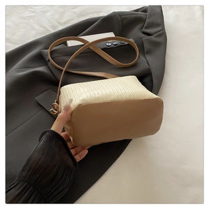 Close-up of stylish two-tone handbag with white pleated texture and brown leather base