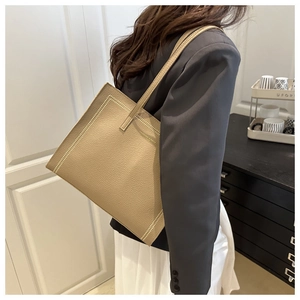 Detail of khaki lychee grain leather tote bag with fine stitching on a shoulder strap
