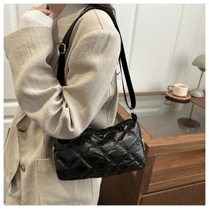 Detail of black quilted shoulder bag in shiny waterproof nylon with golden metal buckles