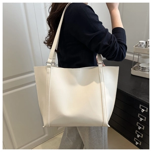 On-shoulder view of large cream tote bag showing real-size fit and premium leather texture