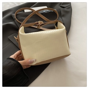 Detail of white pleated texture handbag with brown leather strap and gold hardware