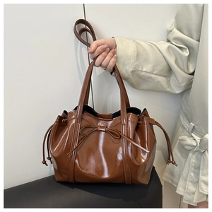 Detail shot of the glossy brown bow-tie tote bag with drawstring side texture