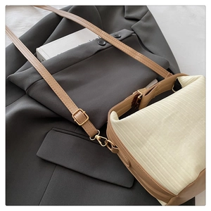 Detail of knitted cream fabric and beige leather strap with gold buckle on crossbody bag