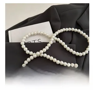 Détail de la bandoulière de remplacement en perles blanches sur fond de blazer noir