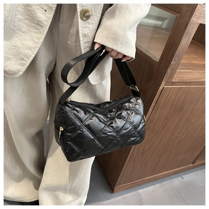 Detailed view of black quilted nylon handbag featuring classic rhombic stitching and gold zipper