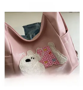 Close-up of pink faux leather bag featuring a detailed puppy embroidery and bow decoration