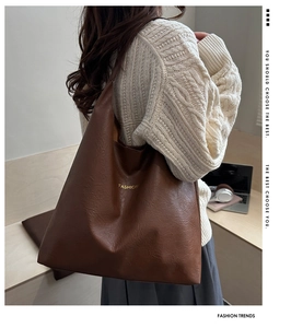 Detail of vintage brown leather tote bag with gold Fashion text on a wooden desk