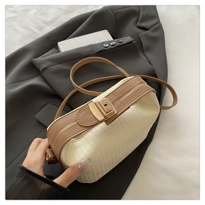 Detail of cream pleated crossbody bag with brown leather trim and golden metal lock