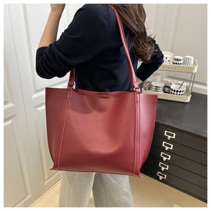 Close-up of burgundy leather tote bag showing matte finish and long shoulder strap