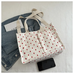 Detail of white corduroy tote bag with red heart prints and functional front pockets