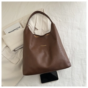 Close-up of the vintage brown leather tote bag texture and golden Fashion lettering