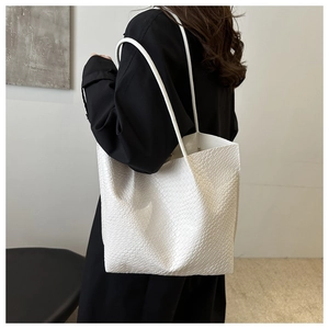 Close-up of white embossed tote bag with crocodile texture and long shoulder straps