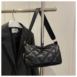 Detail of black quilted shoulder bag with diamond pattern and golden zipper closure