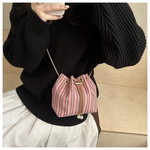 Detail of pink and grey tweed bucket bag featuring pearl drawstring and gold chain strap