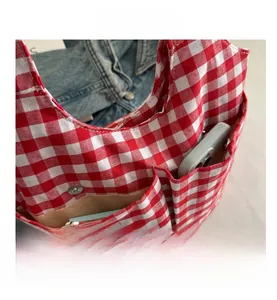 Detail view of red and white gingham canvas bucket bag showing side pockets for phone storage