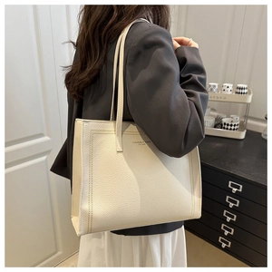 Detail of cream white lychee texture tote bag with gold lettering shown on shoulder