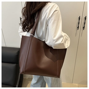 Detailed back view of a minimalist large brown tote bag worn over the shoulder by a model