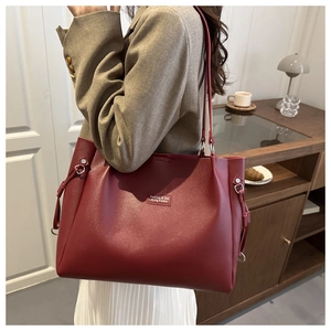 Dettaglio di una borsa tote in pelle bordeaux con coulisse indossata sulla spalla