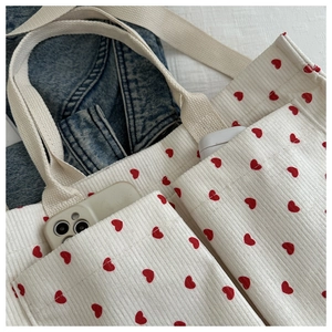 Detail view of corduroy tote bag with red heart pattern and functional front pockets
