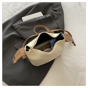 Detailed view of cream pleated crossbody bag with gold zipper showing interior capacity