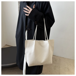 Close-up of woven leather texture on a large cream-colored tote bag with slim straps