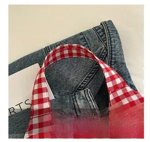Detailed close-up of the red and white checkered tote bag handle with double stitching