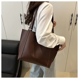 Detail view of large dark brown tote bag with premium leather texture and stitching