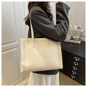 Detail of cream lychee leather tote bag with elegant gold branding and fine stitching