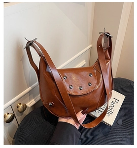 Detail showing vintage brown saddle bag with shiny PU leather and metal rivet accents