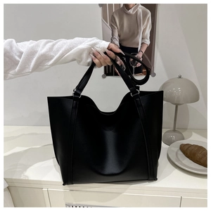 Macro detail of black tote bag featuring matte faux leather and metal ring reinforcements