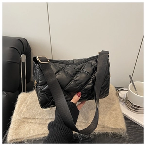 Detail of black quilted shoulder bag with rhombus stitching and adjustable strap