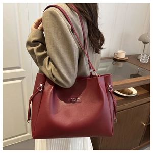Dettaglio della borsa tote bordeaux in similpelle con etichetta logo e fibbie laterali