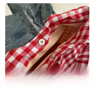 Detail of metal magnetic closure on a red checkered bucket bag with denim background