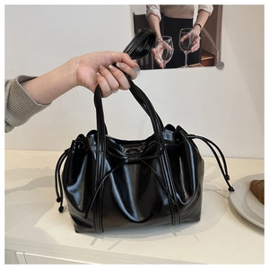 Detailed close-up of a glossy black tote bag with bow accent and drawstring cloud design