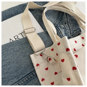Detail of white corduroy crossbody bag with red heart pattern and adjustable strap