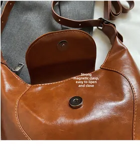 Detail shot of a brown vintage leather shoulder bag featuring a strong magnetic snap closure