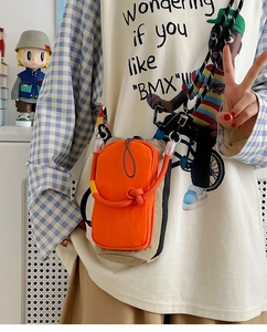 Détail de la sacoche utilitaire orange avec corde tressée et bandoulière à motifs à pois