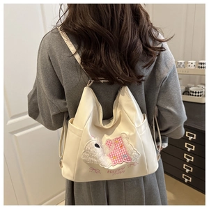 Detail of beige backpack featuring a plush puppy patch and Happy Puppy text embroidery