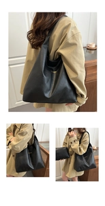 Detail view of large black leather tote bag with gold lettering and small zipper pouch