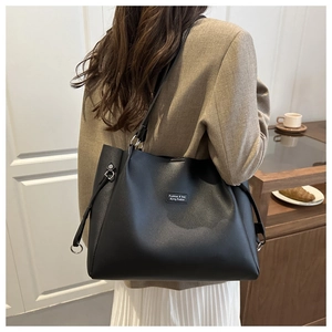 Dettaglio della grande borsa tote nera con grana fine e etichetta alla moda cucita